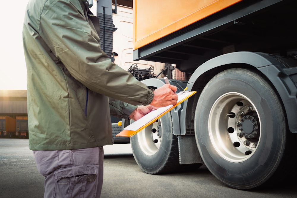 man writing on clipboard beside truck
