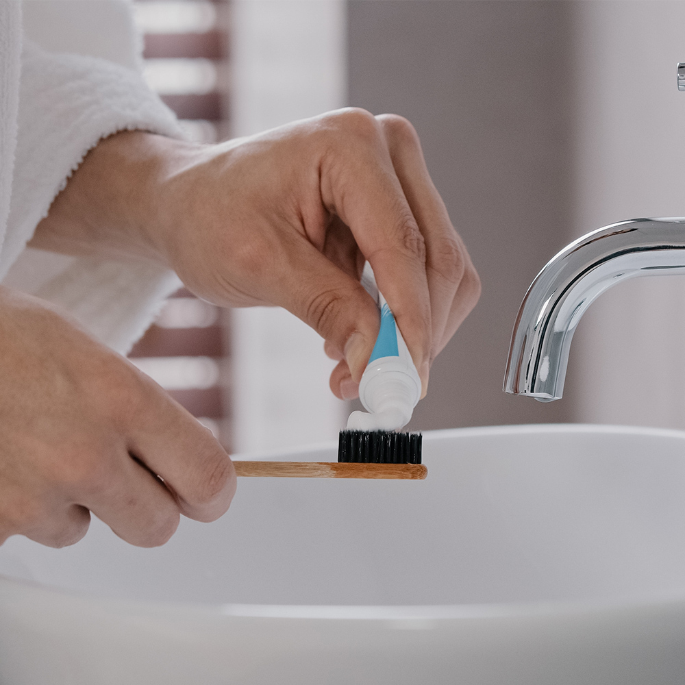 Person putting toothpaste on a toothbrush