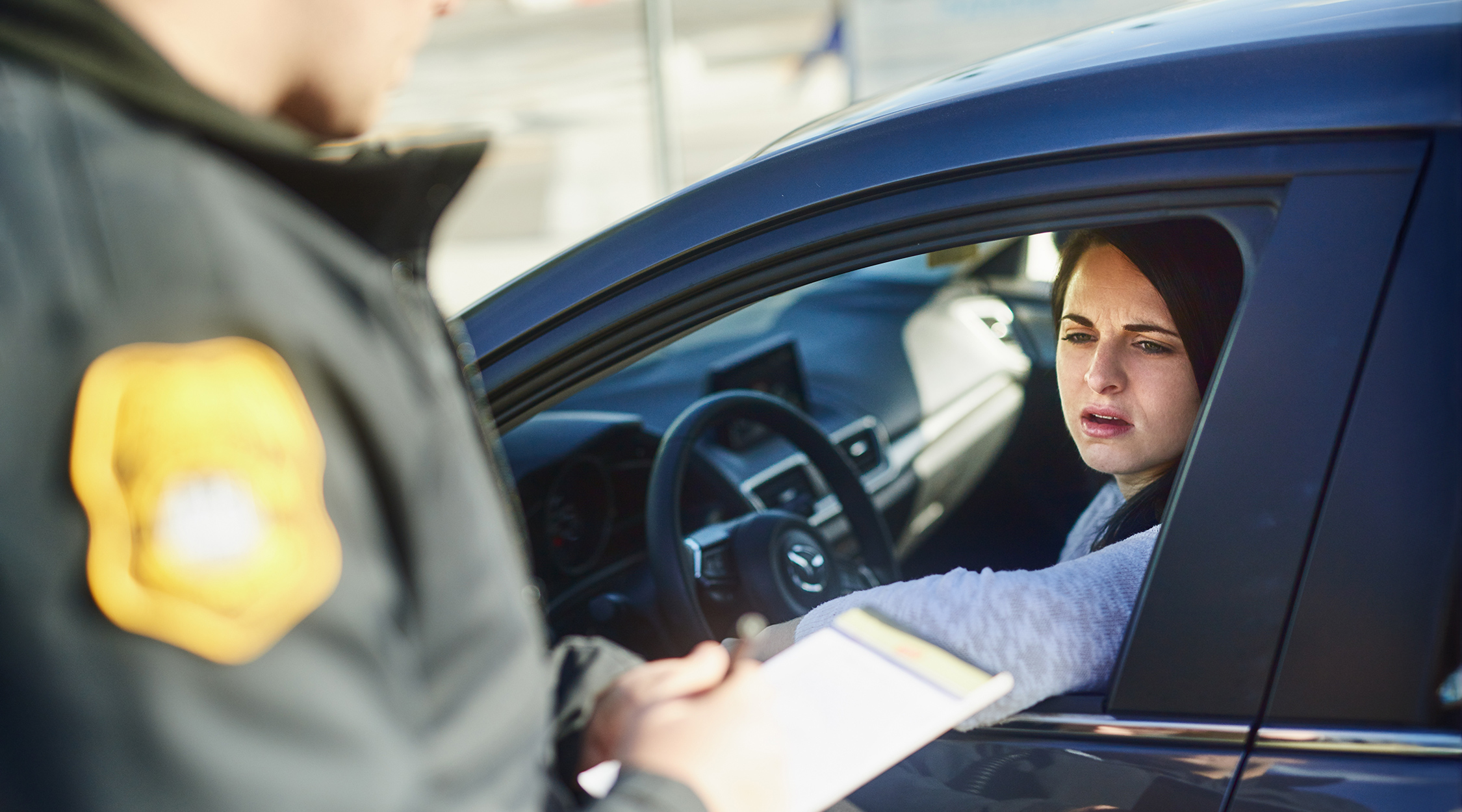 woman in car receiving a ticket from a police officer