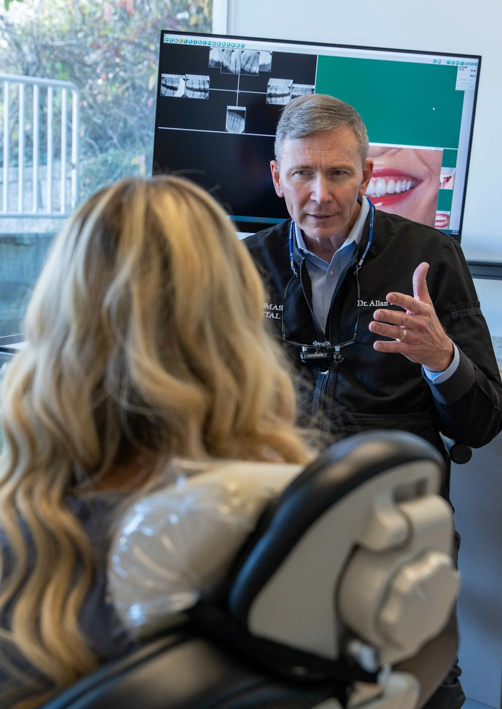 Dr. Allan S. Thomas consulting with a patient in front of dental imaging screen