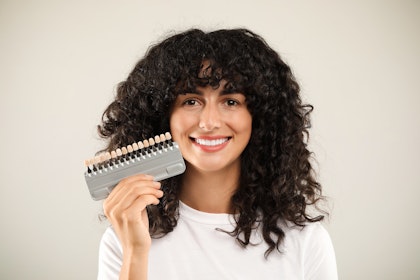 woman smiling while holding up shade matcher