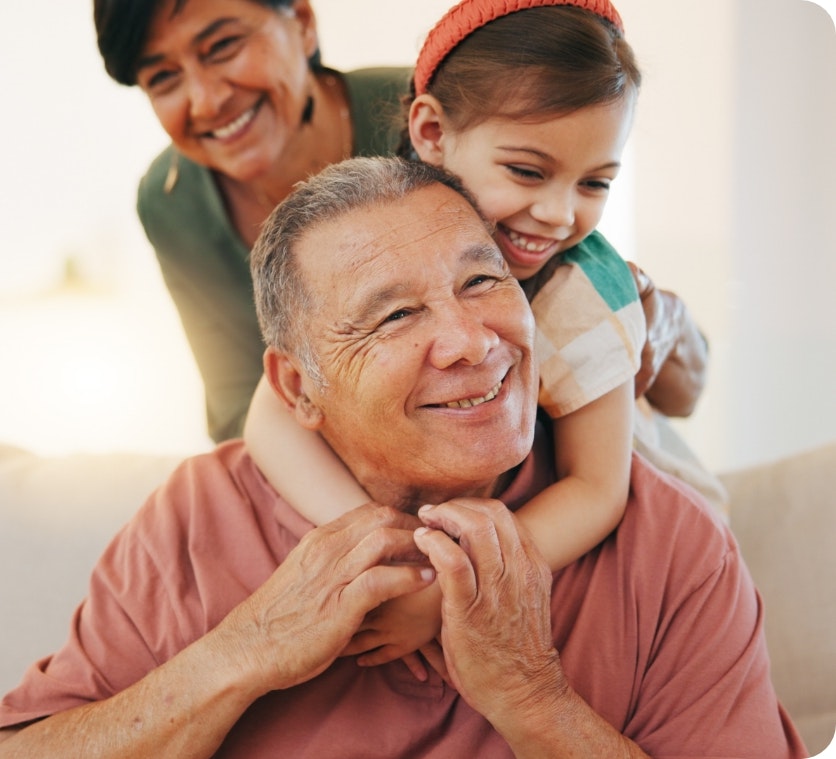 Man smiling with his granddaughter and wife