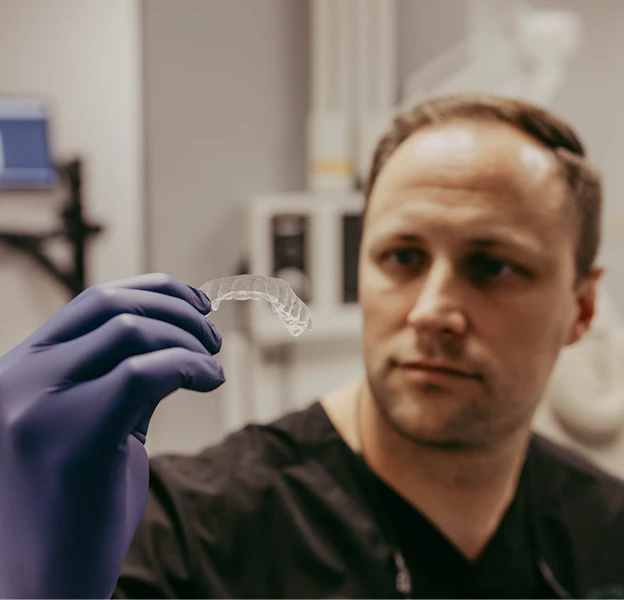 Dr. Chandler looking at an Invisalign in hand
