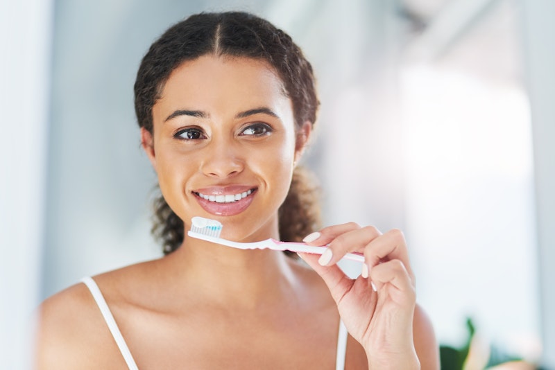 Woman smiling in mirror while holding toothbrush