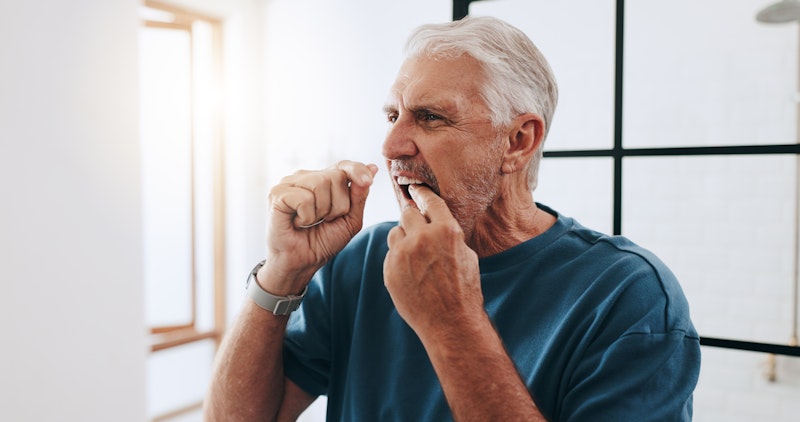 Senior man flossing his teeth