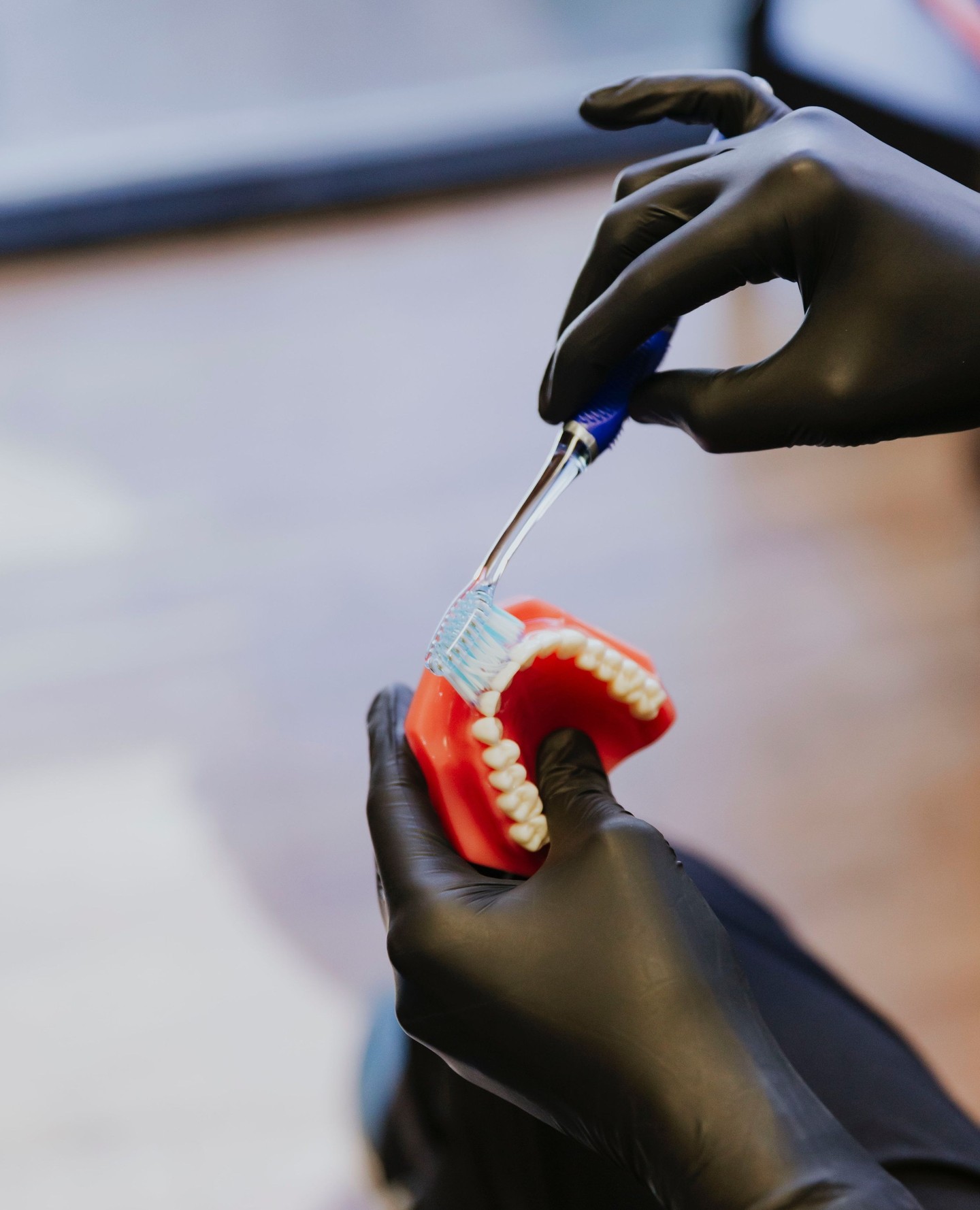gloved hands brushing a dental arch model