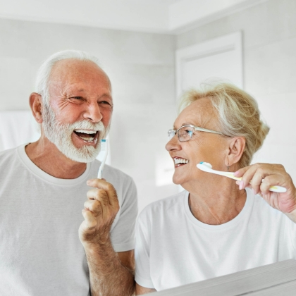 Older couple with implants brushing teeth together
