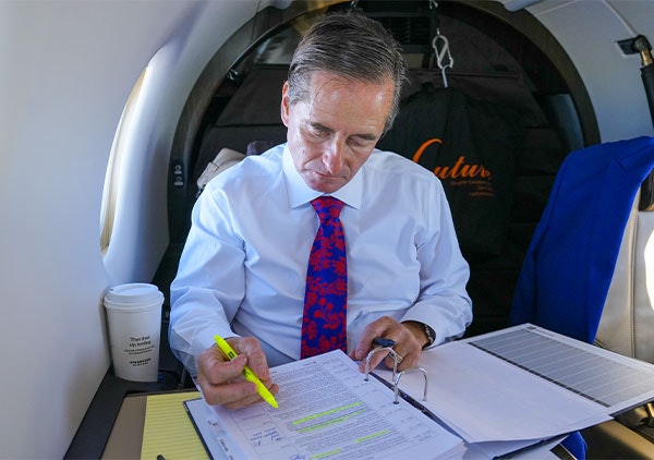 CHRIS DOLAN REVIEWING DOCUMENTS ON A FLIGHT
