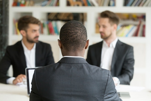Back view of an african businessman talking to two caucasian men in suits