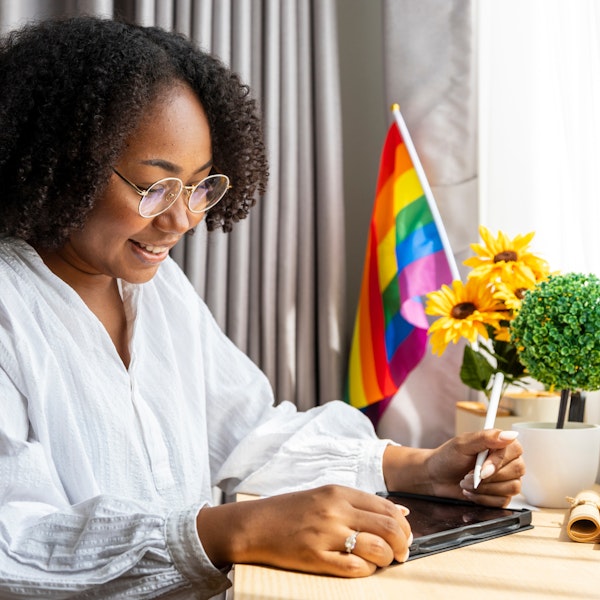 Woman working with an LGBTQ+ flag at her desk