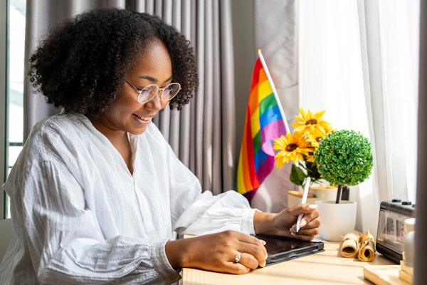 Woman working with an LGBTQ+ flag at her desk