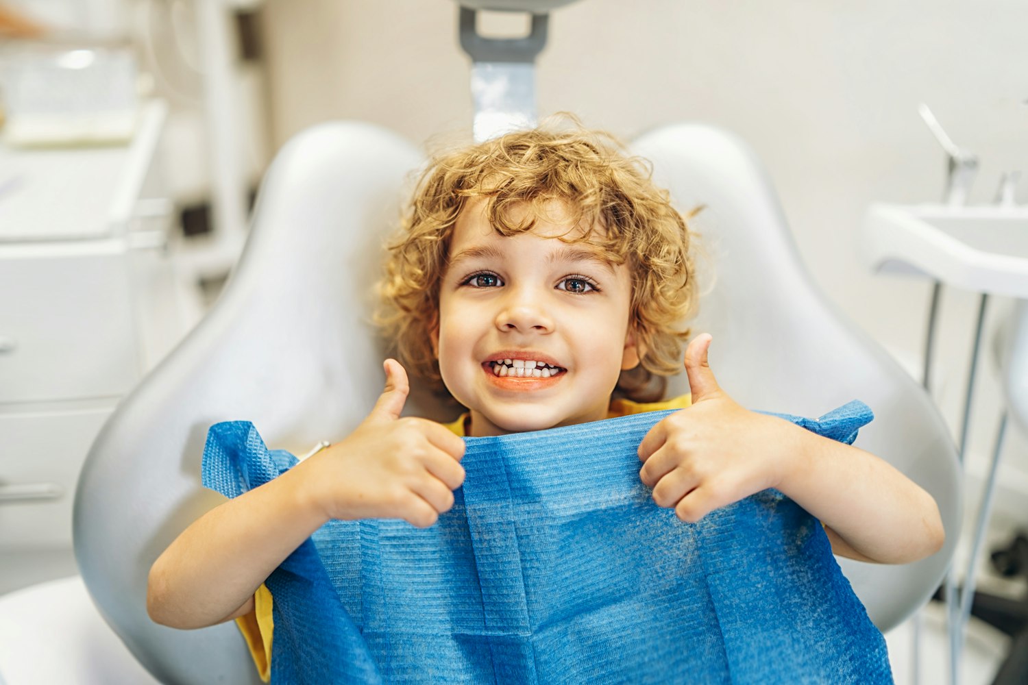 Smiling young boy giving thumbs up in the dental chair