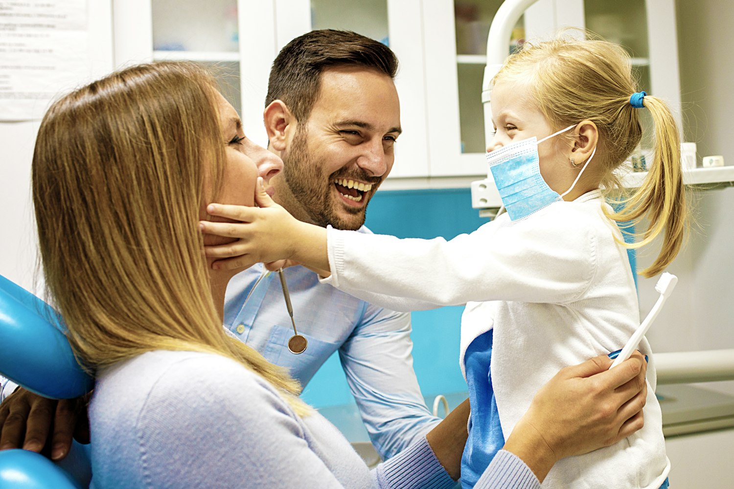 Laughing dentist with a mom and her young girl