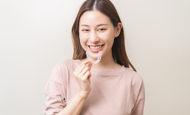Woman smiling while holding Invisalign