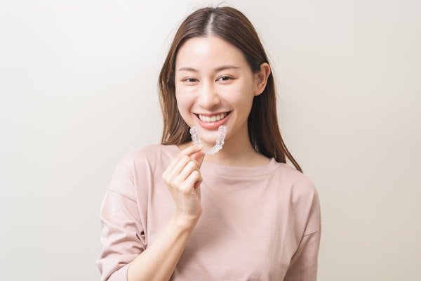 Woman smiling while holding Invisalign