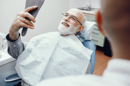 Mature man smiling in a mirror at the dentist