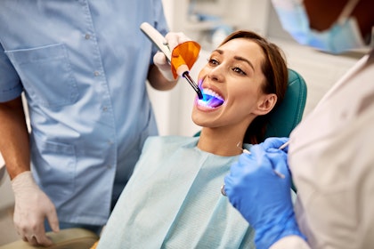 Dentist using curing light for dental bonding on patient