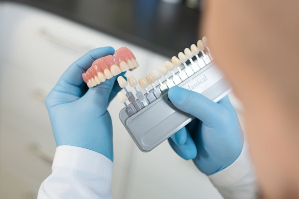 Dentist holding veneers up to a dental model