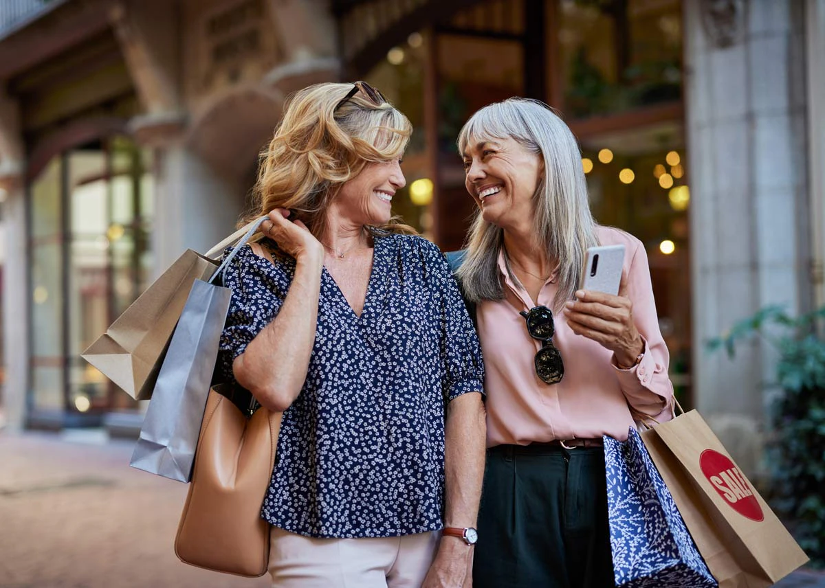 two women with shopping bags smiling