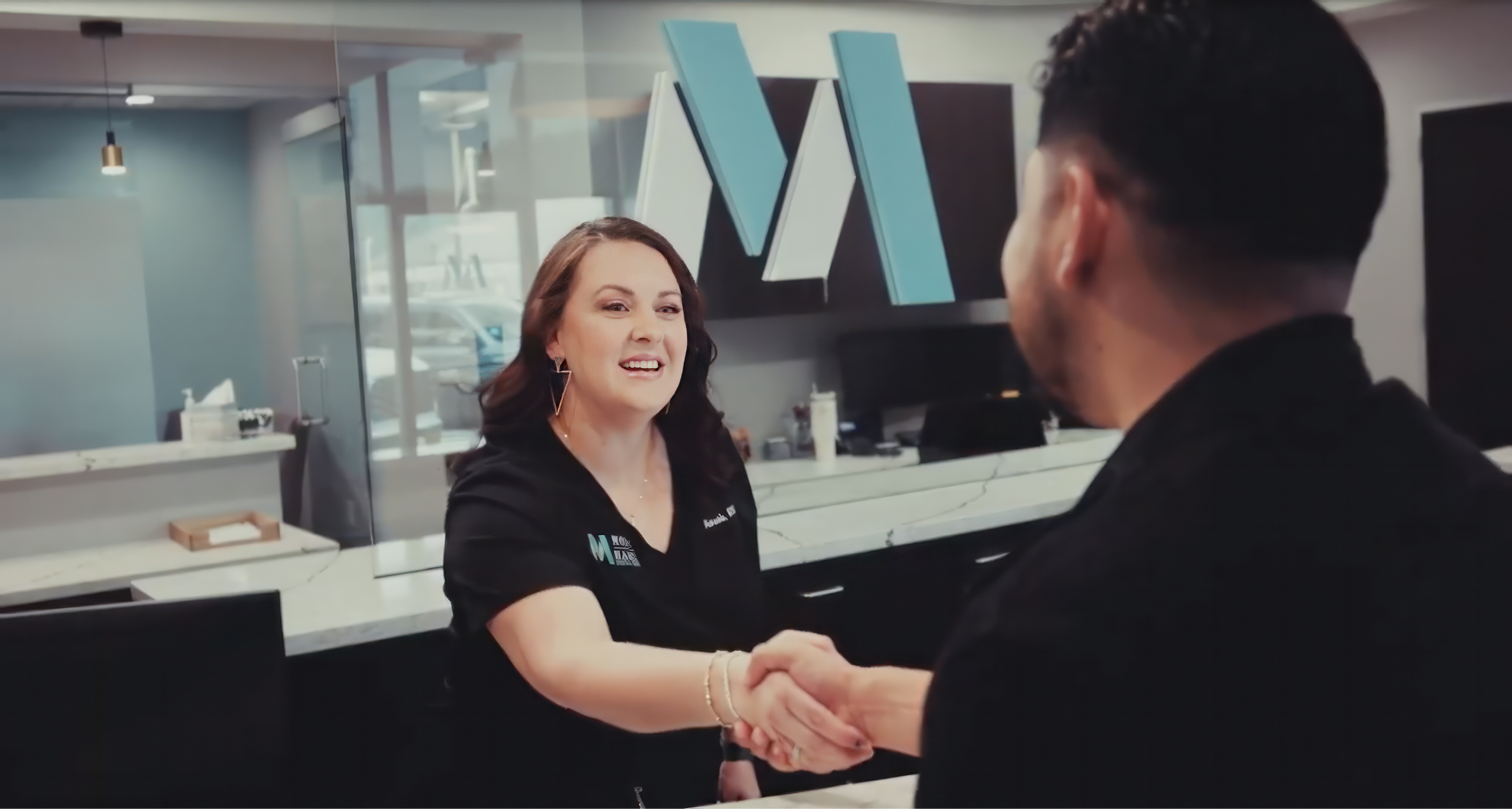 Dental team member greeting a patient with a handshake at Montz & Maher Dental Group front desk