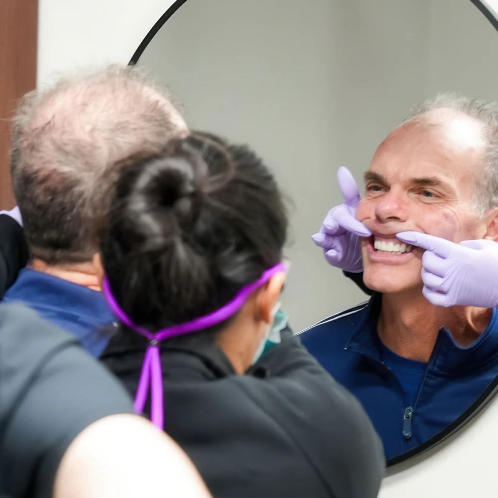 Real Montz and Maher patient looking at their smile in the mirror