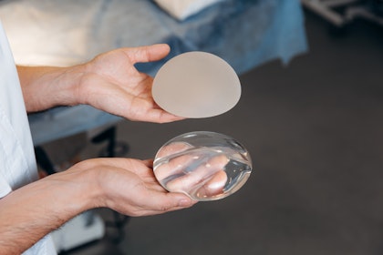 hands holding two types of breast implants