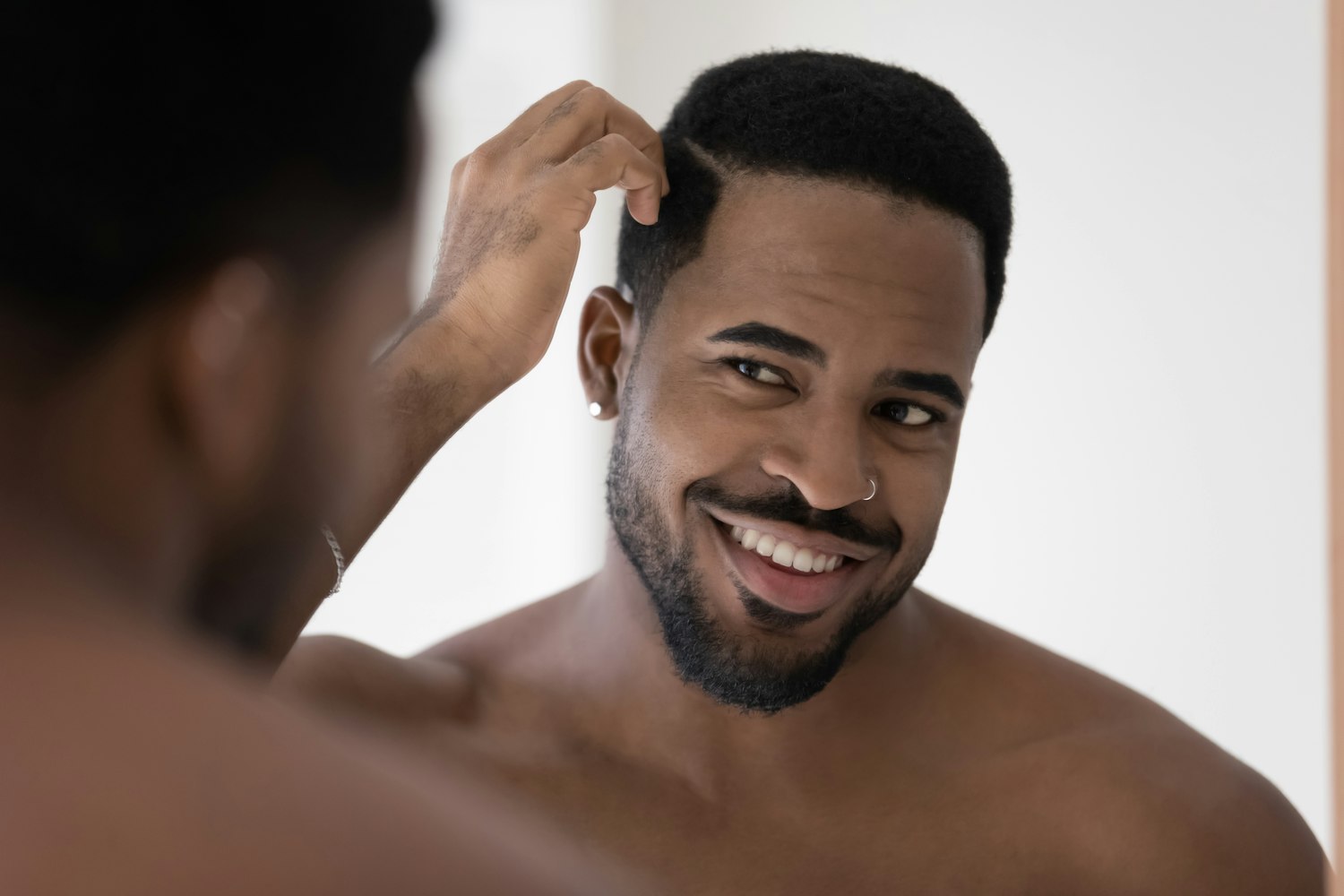 man smiling and examining his scalp
