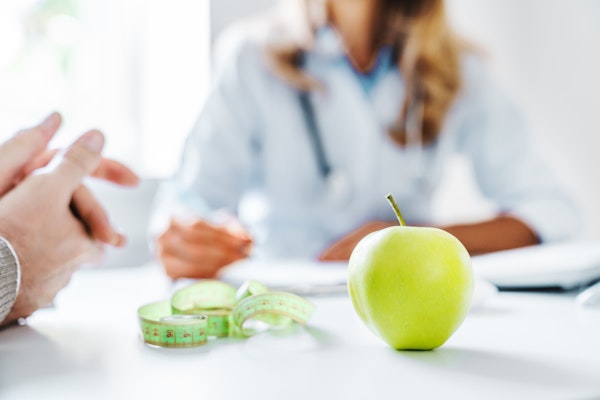 Apple and tape measure on the desk during a nutrition consultation