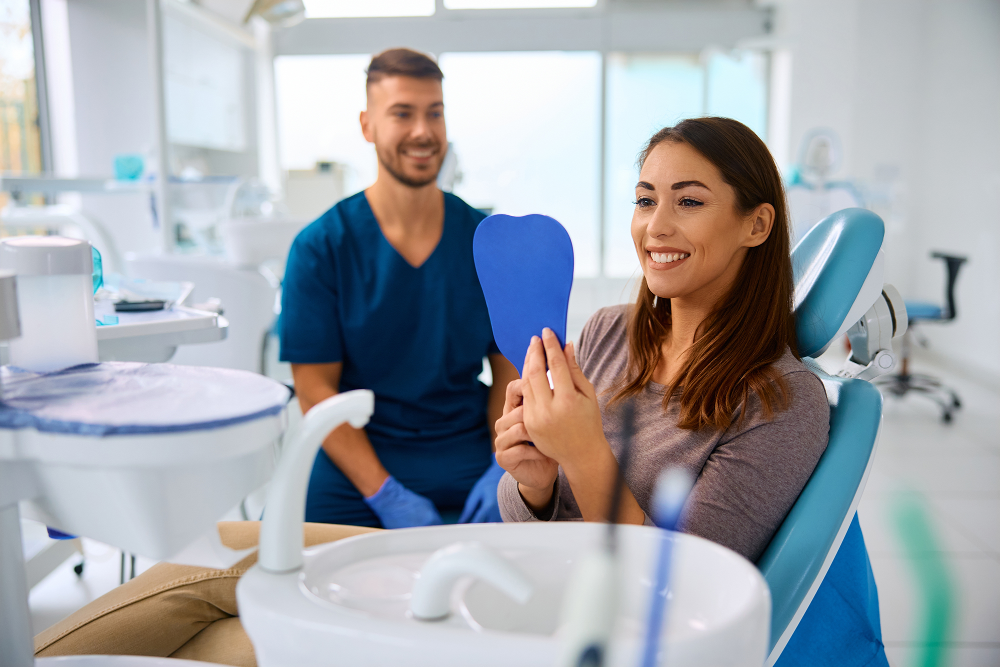 dental patient smiling in a handheld mirror