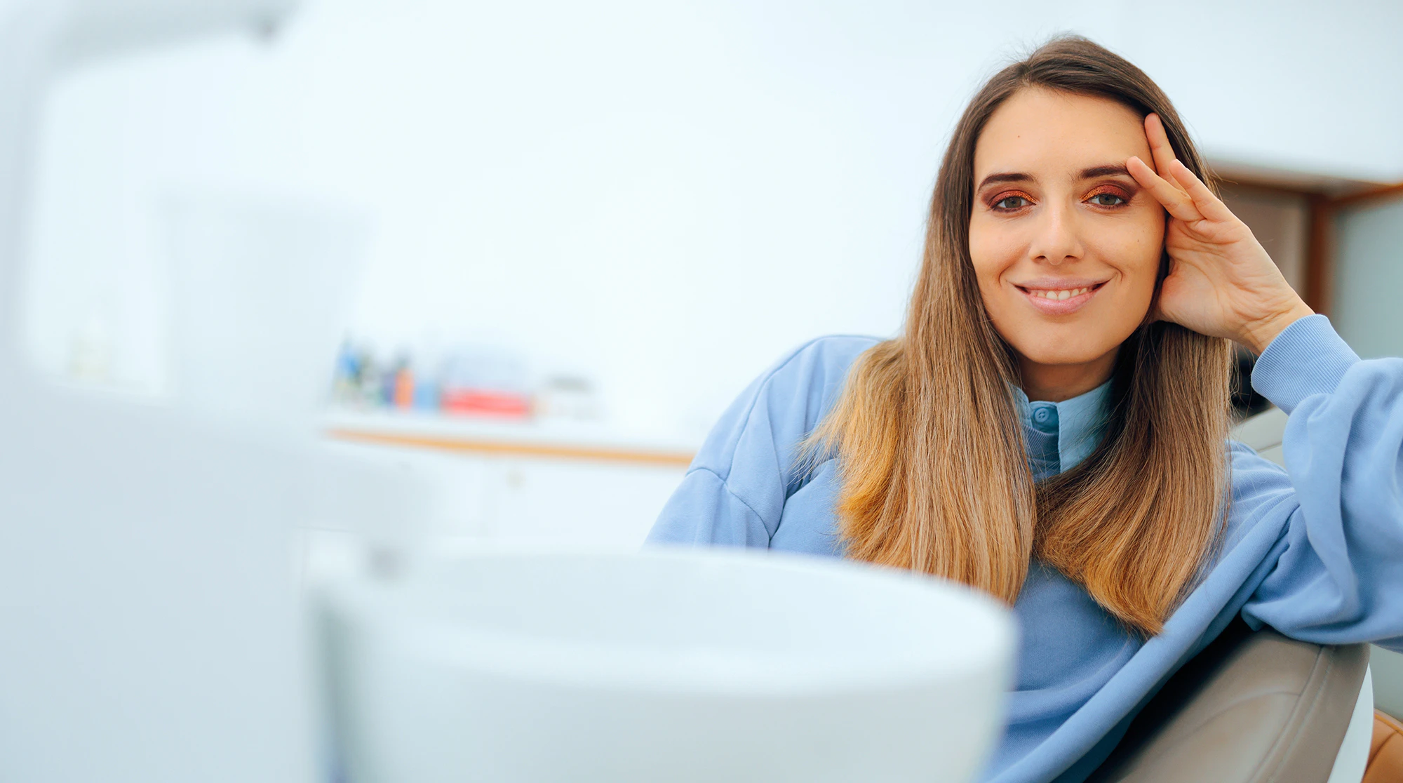 Woman smiling while relaxing in a dental chair inside a modern dental office.
