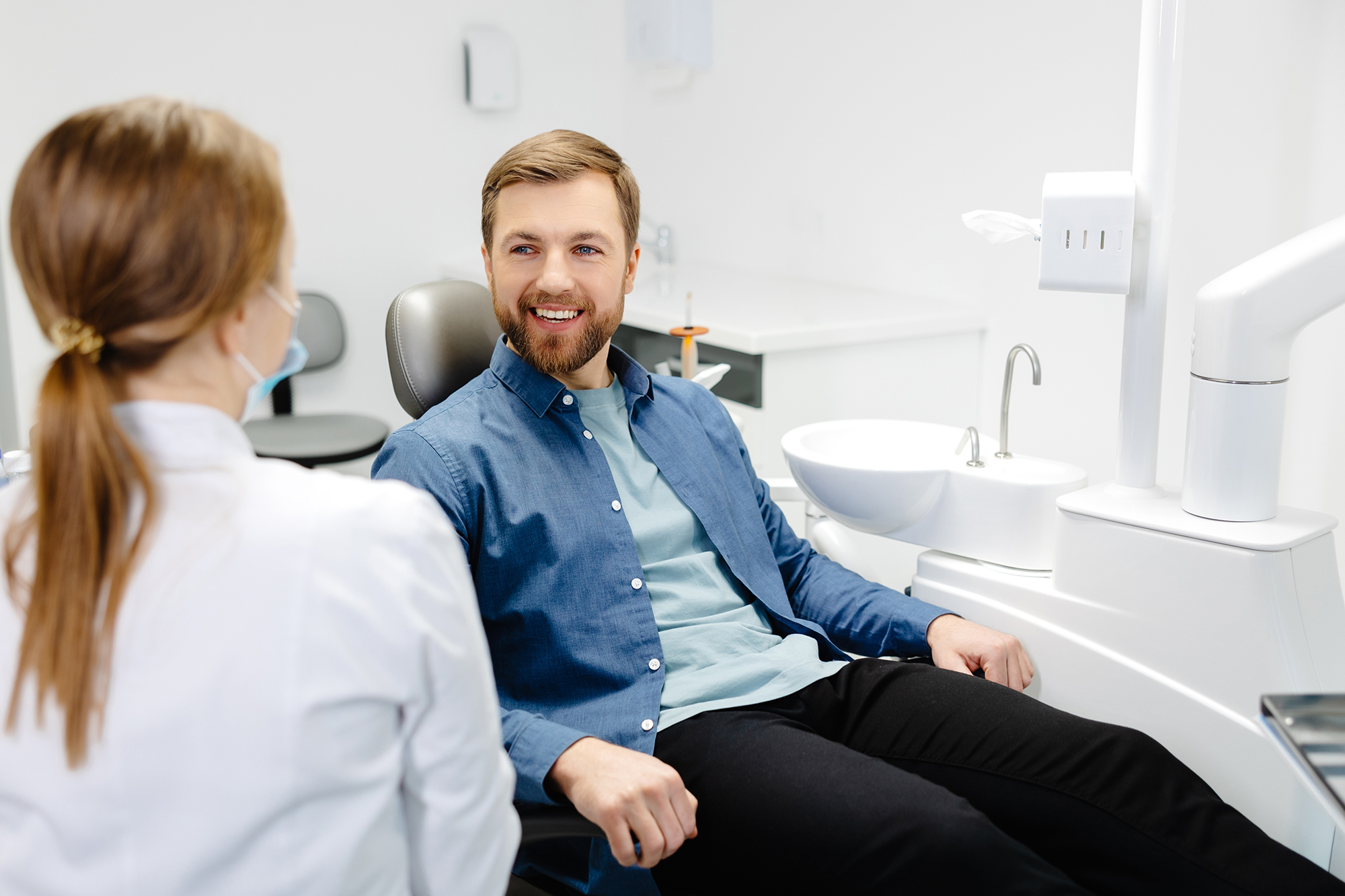 Man smiling while speaking with a dental professional during a consultation in a dental exam room.
