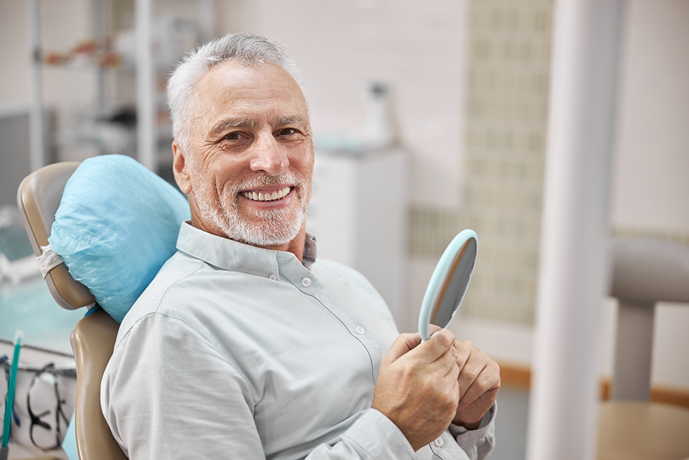 Dentist wearing blue gloves gently adjusting a young woman’s smile during a dental exam.
