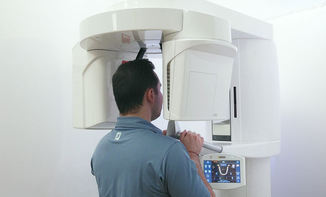 Man smiling while speaking with a dental professional during a consultation in a dental exam room.