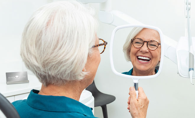 Senior woman smiling in handheld mirror