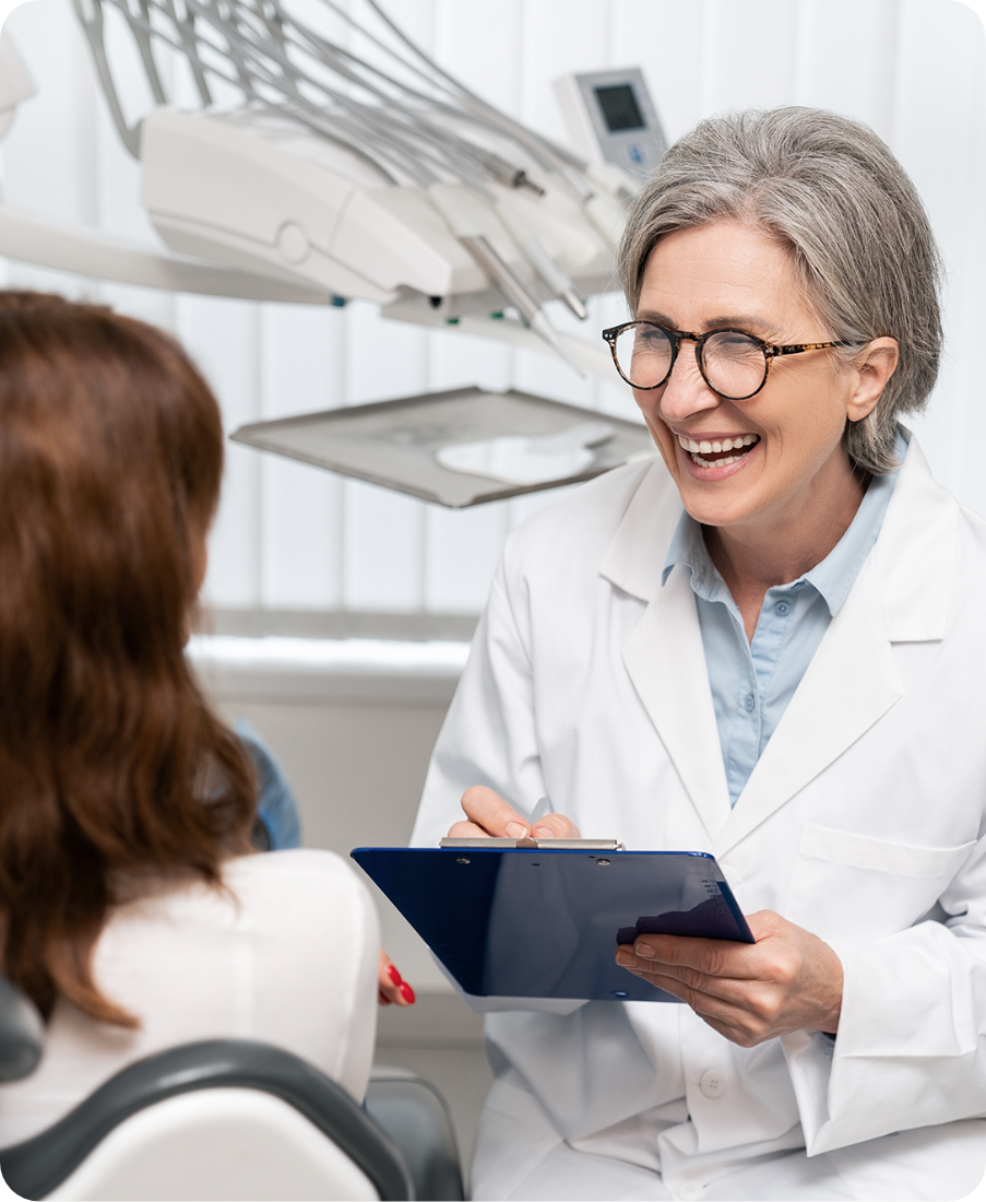 Smiling female dentist holding clipboard during patient consultation