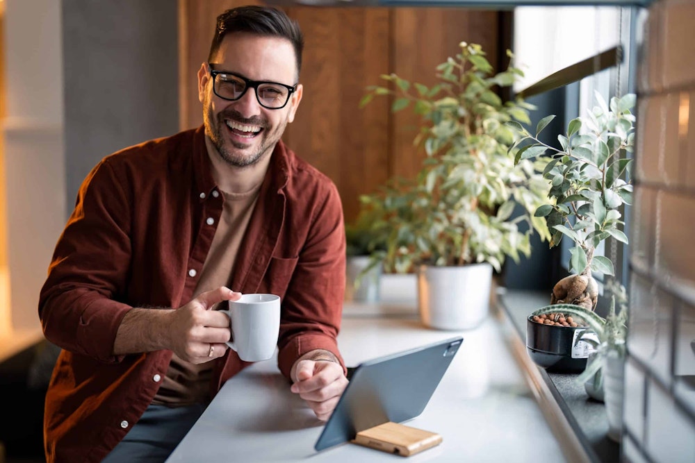 man in glasses smiling holding a mug
