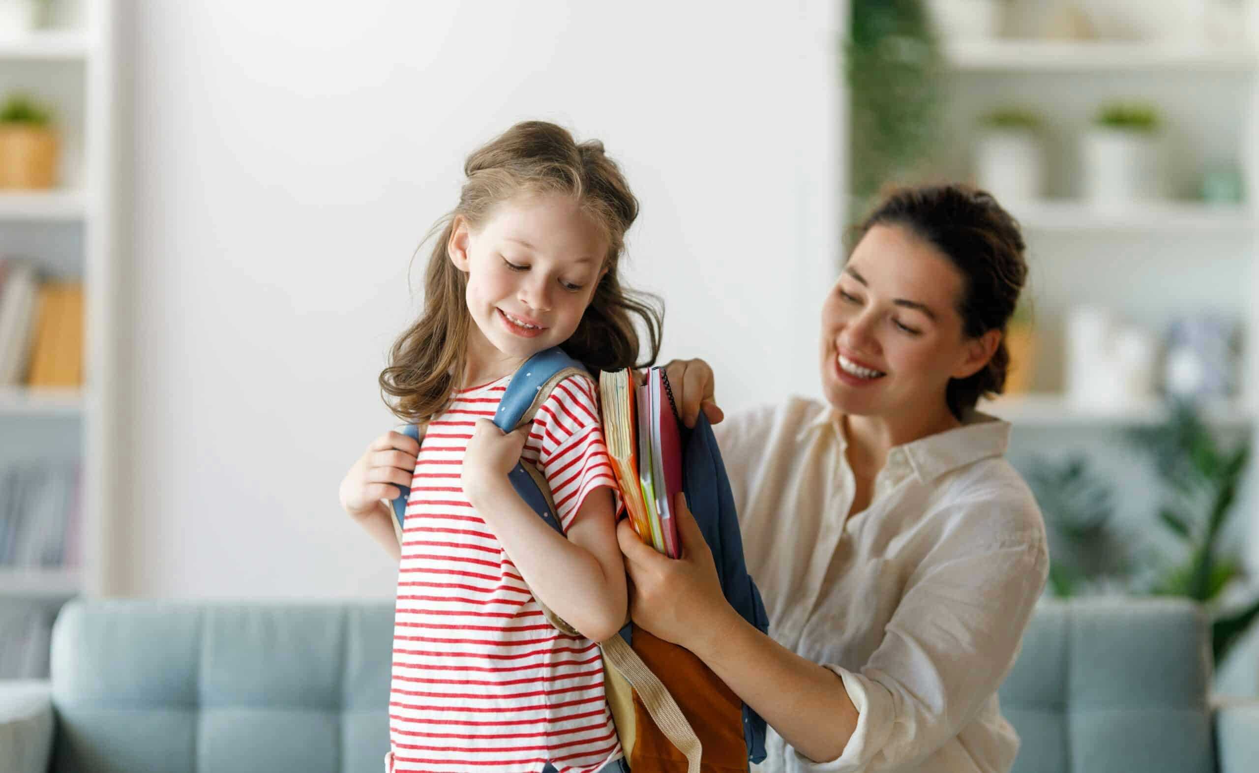 mom helping young daughter and smiling
