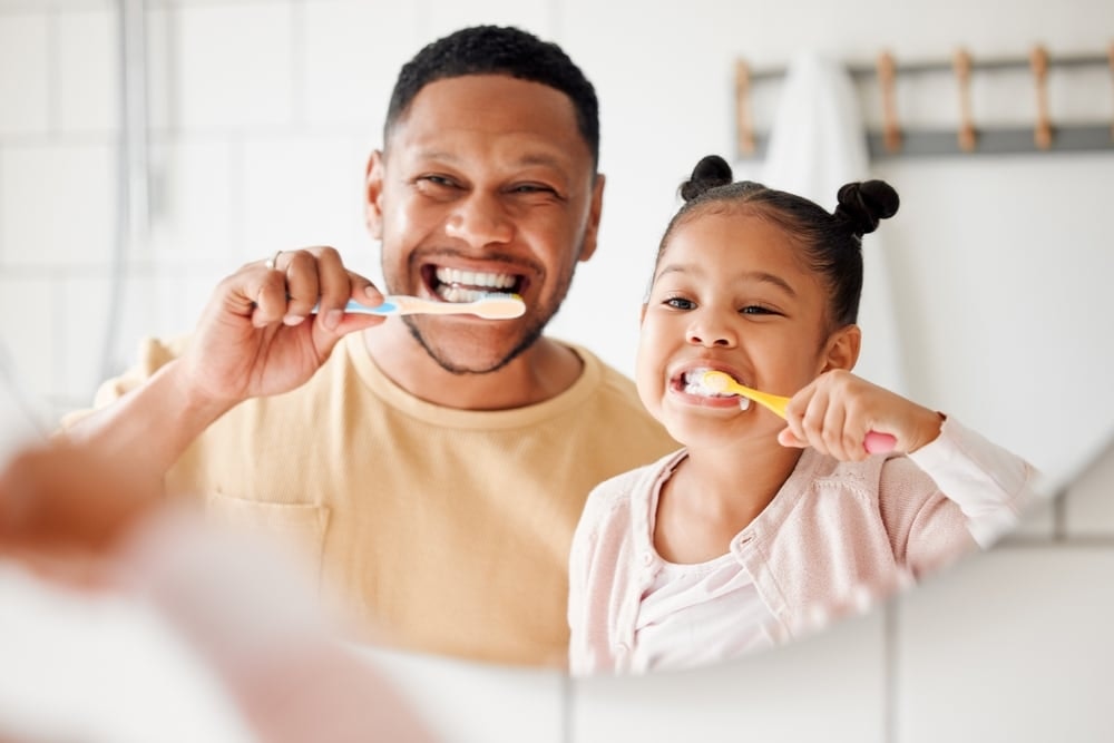 man and daughter brushing teeth