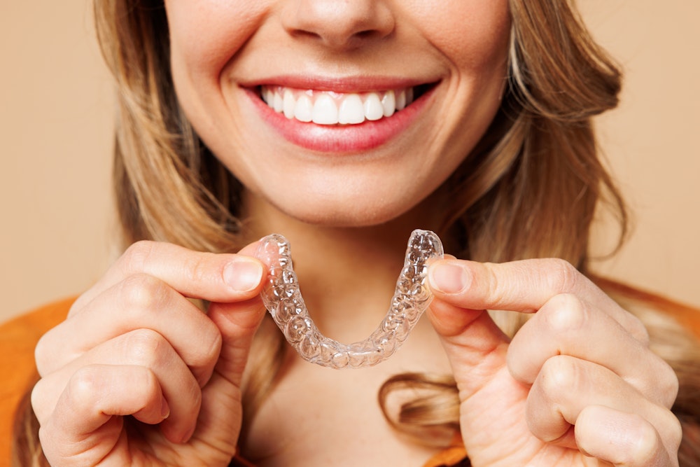Smiling woman holding a clear aligner