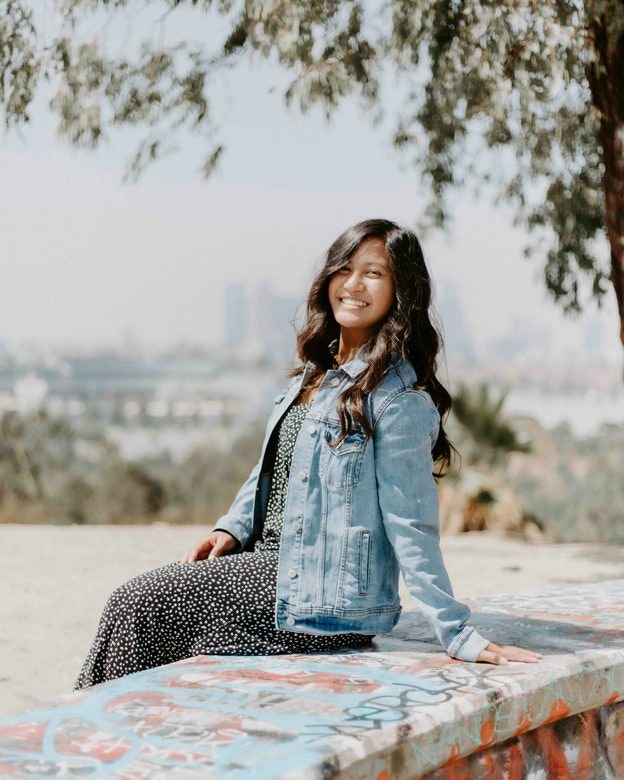 Smiling young woman sitting on park bench