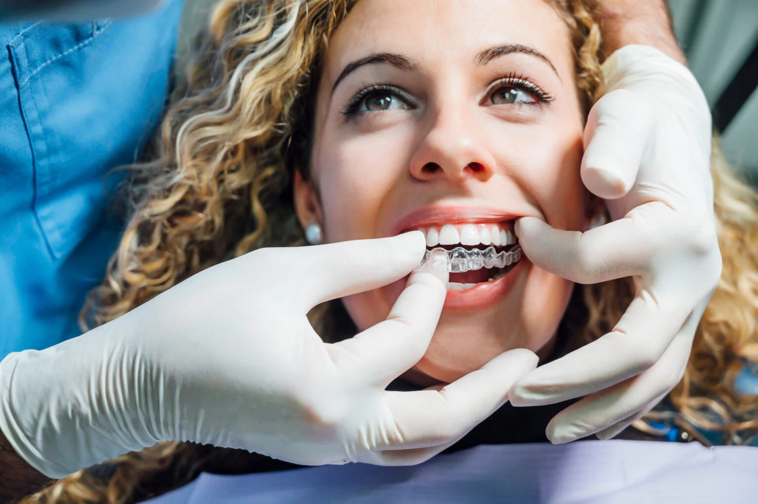 young woman and dentist inserting aligner tray