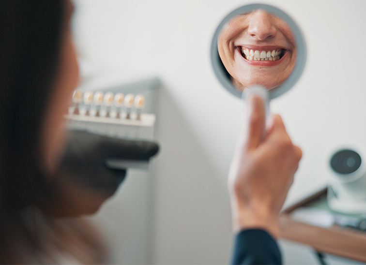 Patient smiling into a handheld mirror.