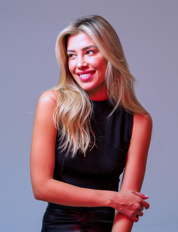 blonde woman against a blue background smiling
