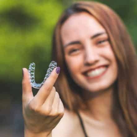 woman holding clear aligner