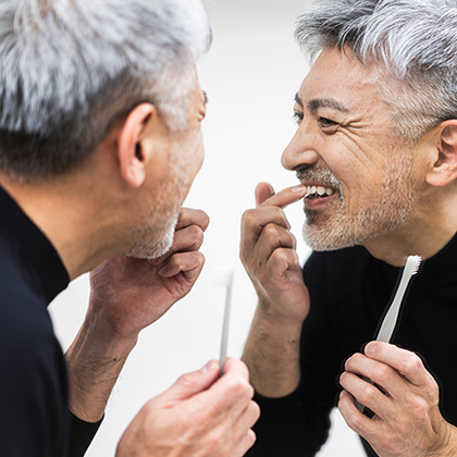 man examining gums in mirror