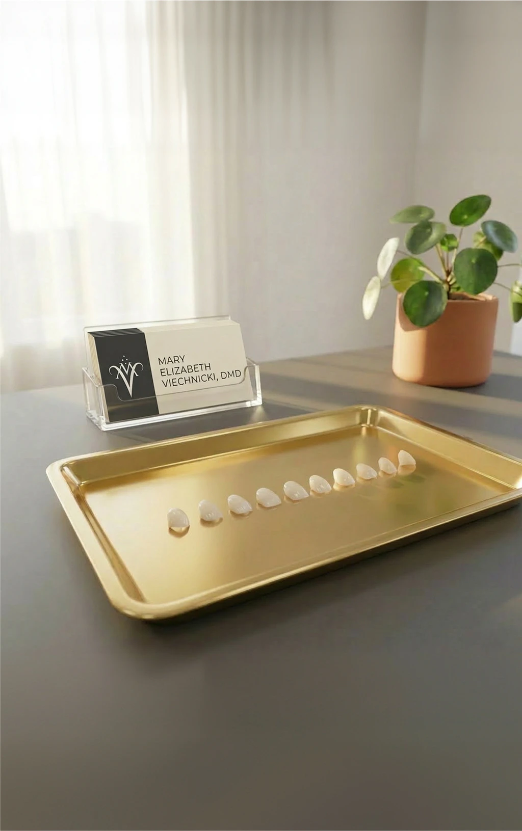 Porcelain no-prep veneer samples displayed on a gold tray beside Mary Elizabeth Viechnicki, DMD business cards