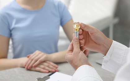 dentist holding a dental implant model