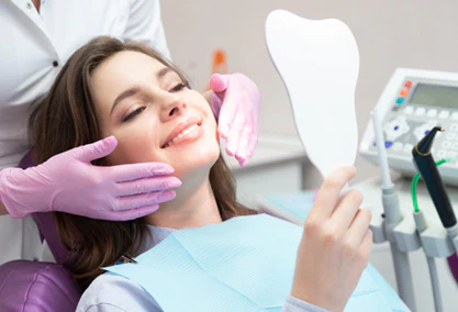 dental patient smiling in handheld mirror