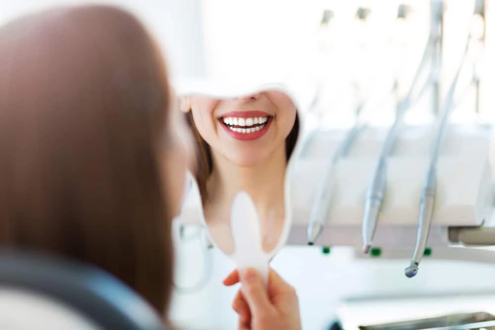 woman smiling in handheld mirror