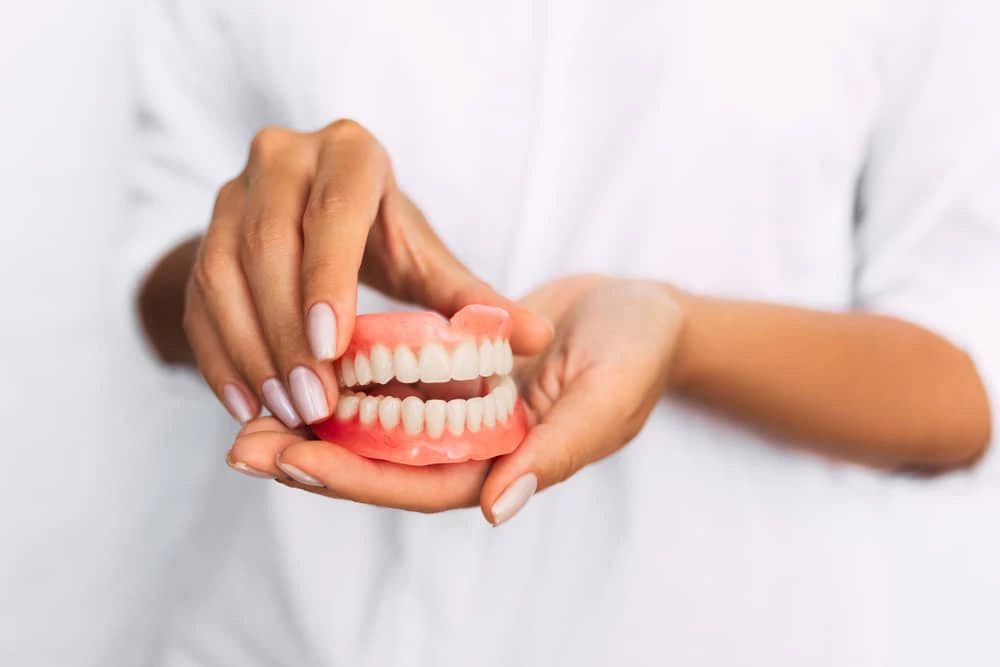hands holding a pair of dentures